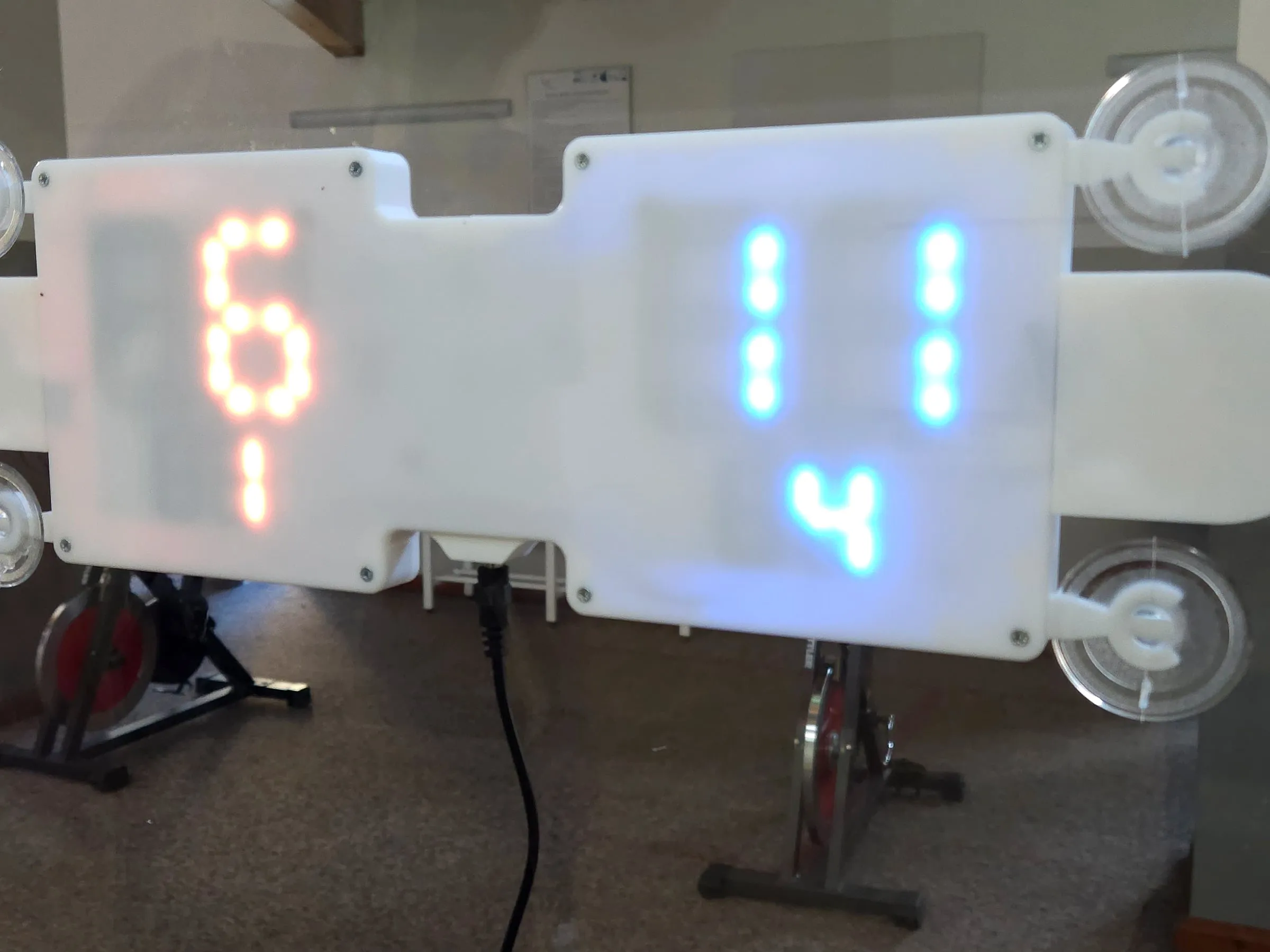 Close-up of the scoreboard from the court side: both players' red and blue digits on the white case