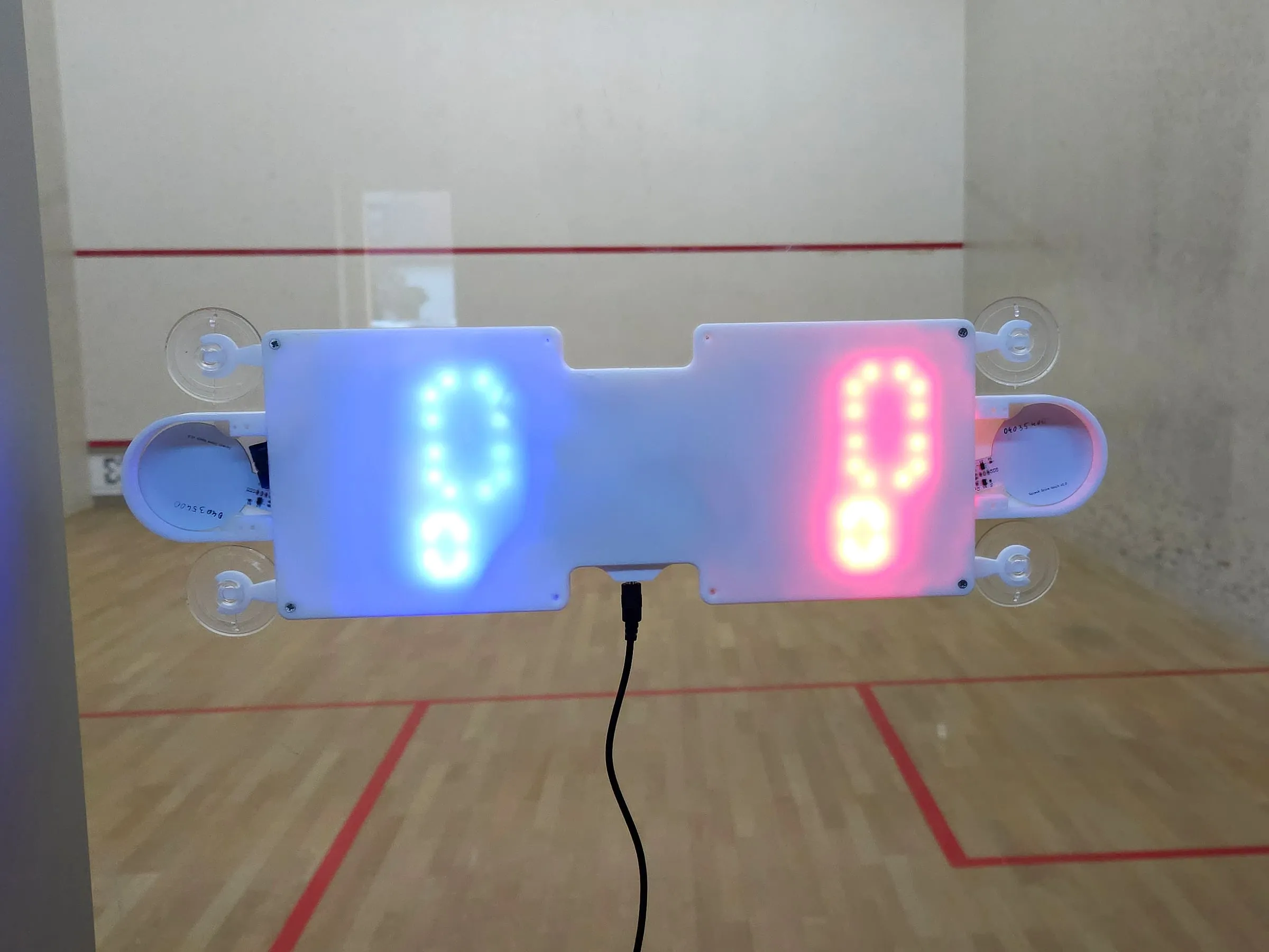 The scoreboard on the back glass wall, with an empty court behind it